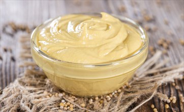 Portion of Mustard in a small bowl on wooden background