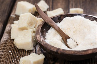 Grated Parmesan Cheese on dark wooden background (detailed close-up shot)