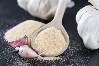 Wooden Spoon with Garlic Powder on dark background