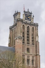 Close-up of a gothic church tower with clocks and a weather vane, dominating the cityscape,