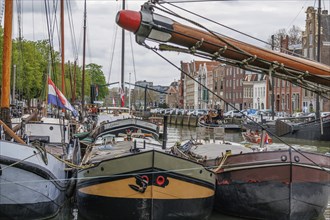 Several boats moored in the harbour, with a colourful background of buildings and flags, Dordrecht,