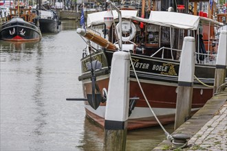 Detailed boat in the harbour, moored to pillars with anchor and white ropes in the foreground,