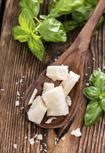 Parmesan Cheese with Basil on an old wooden table (close-up shot)