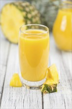 Pineapple Juice as high detailed close-up shot on a vintage wooden table, selective focus