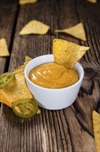 Nachos with Cheese Sauce (close-up shot) on wooden background