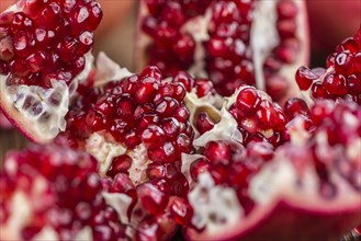 Pomegranate on an old wooden table as detailed close-up shot (selective focus)