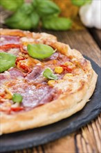 Fresh made Salami Pizza with basil on wooden background