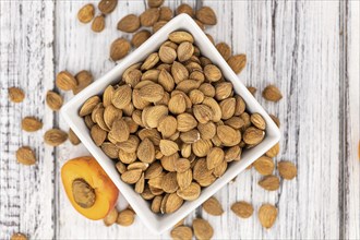 Vintage wooden table with a portion of shelled Apricot Kernels (close up shot, selective focus)