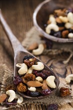 Portion of mixed nuts and fruits (trail mix) on wooden background