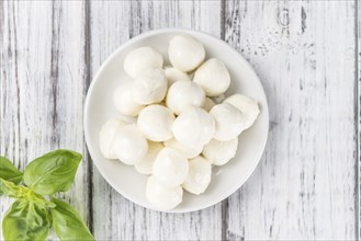 Small Mozzarella balls (on wooden background, selective focus) as close-up shot