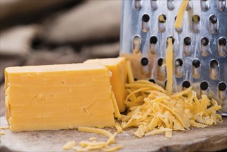 Portion of grated Cheddar Cheese on rustic wooden background