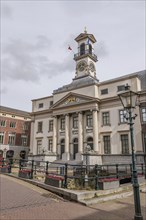 Magnificent town hall with columned faÃ§ade and clock tower, surrounded by old town houses under a