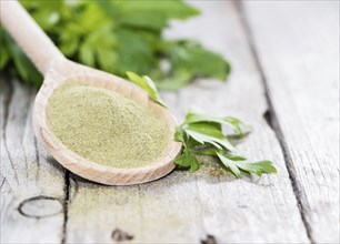 Lovage Powder on a wooden spoon with some fresh green leaves