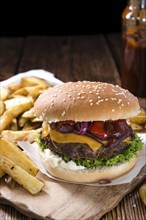 Big Burger with homemade French Fries on rustic wooden background