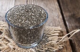 Chia Seeds in a small bowl (on dark wooden background)