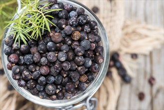 Dried Juniper Berries on wooden background (close-up shot)