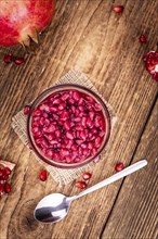 Some preserved Pomegranate seeds on a vintage wooden table (selective focus, close-up shot)