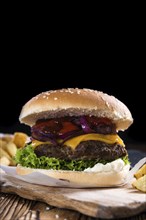 Big fresh made Burger on rustic wooden background (with French Fries)