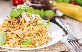 Spaghetti and Tomato Pesto on wooden background (close-up shot)