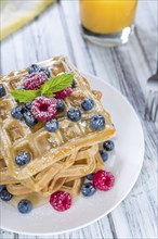 Waffles with mixed Berries and Honey (detailed close-up shot) on wooden background