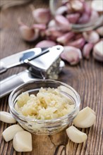 Crushed Garlic (close-up shot) on rustic wooden background