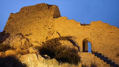 Night shot, close-up of an illuminated old castle ruin with stone steps and an archway at night,