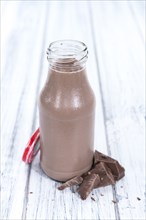 Chocolate Milk in a small bottle (on bright wooden background)