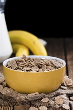 Bowl with Wholemeal Cornflakes (close-up shot) on a wooden table