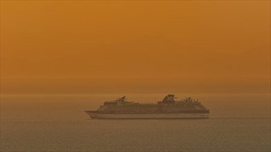 Large cruise ship sails through the calm, orange-coloured sea at sunset, Kritinia Castle, St John's