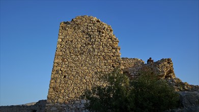 An old, ruined stone tower on a rock under a clear sky, Kritinia Castle, St John's Castle,