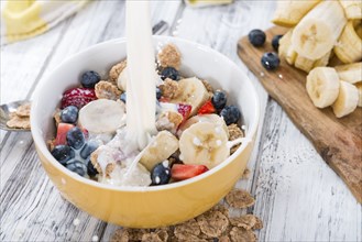 Cornflakes with fresh Fruits and Milk on a wooden table