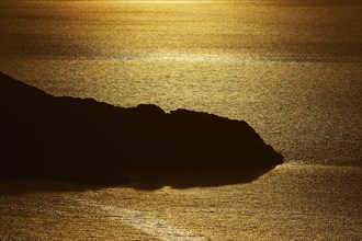 Coastal silhouette at sunset, the golden light reflected in the calm water, Kritinia Castle, St