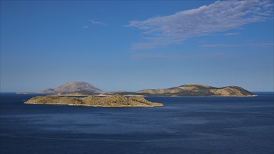 View of several islands in the blue sea under a clear sky with light clouds, Makri Island, Alimia