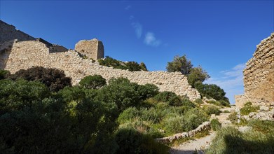 Path along the ruins of an ancient castle, surrounded by green vegetation and blue sky, Kritinia