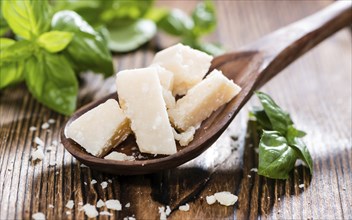 Portion of Parmesan Cheese with Basil on wooden background