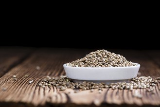 Portion of Hemp Seeds (close-up shot) on an old wooden table