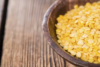 Yellow Lentils (detailed close-up shot) on wooden background