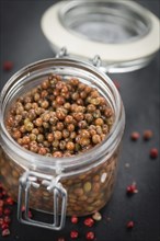 Some Pink Peppercorns (preserved) on a slate slab as detailed close-up shot, selective focus