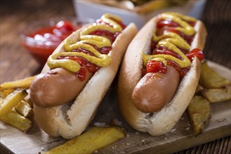 Hot Dog with ketchup and mustard (close-up shot) on wooden background