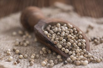 Portion of white Peppercorns (close-up shot) on vintage wooden background