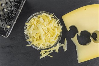 Homemade Grated Cheese (close-up shot) on a vintage slate slab