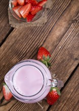 Fresh made Strawberry Milk on an old wooden table (selective focus)