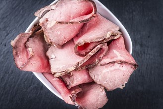 Portion of sliced Roastbeef on a slate slab (selective focus)