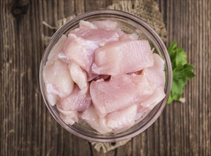 Fresh Chicken Fillet (chopped) as detailed close-up shot on wooden background (selective focus)