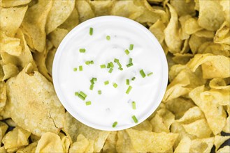 Fresh made Potato Chips with Sour Cream taste on a vintage background (close-up shot)