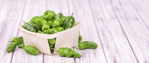 Raw Pimientos on rustic wooden background as close-up shot