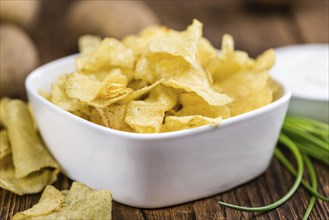 Potato Chips with Sour Cream taste as high detailed close-up shot on a vintage wooden table