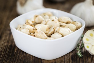 Garlic (preserved) as high detailed close-up shot on a vintage wooden table (selective focus)