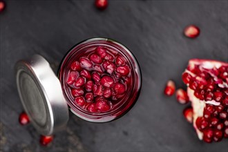 Portion of healthy preserved Pomegranate seeds on a slate slab (selective focus)