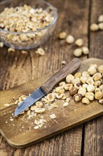 Portion of freshly chopped Hazelnuts on an old wooden table as detailed close up shot (selective